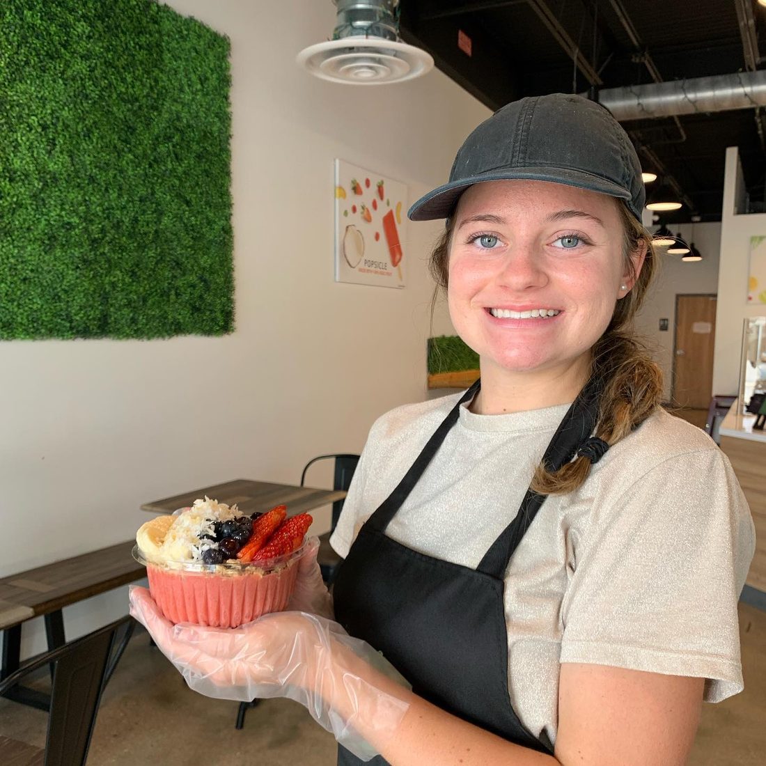 Smiling Sunset Island team member holding an açaí bowl